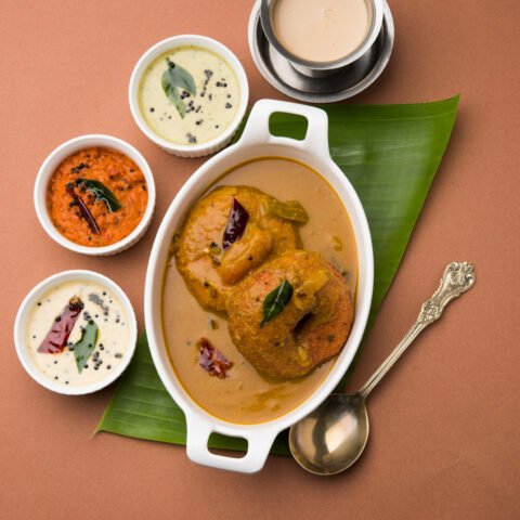 Sambar vada or Medu Vada, a popular South Indian food served with Green, Red and coconut chutney over moody background. Selective focus